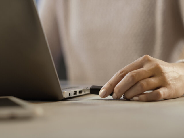 Woman plugging a USB flash drive into her laptop
