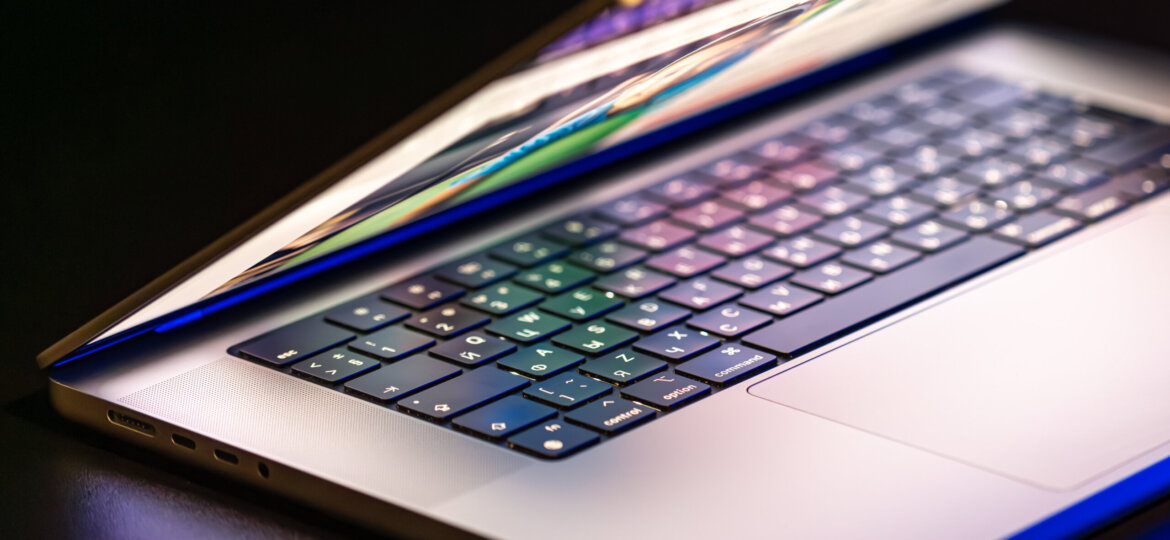 A laptop computer with a half-open screen on a dark background.