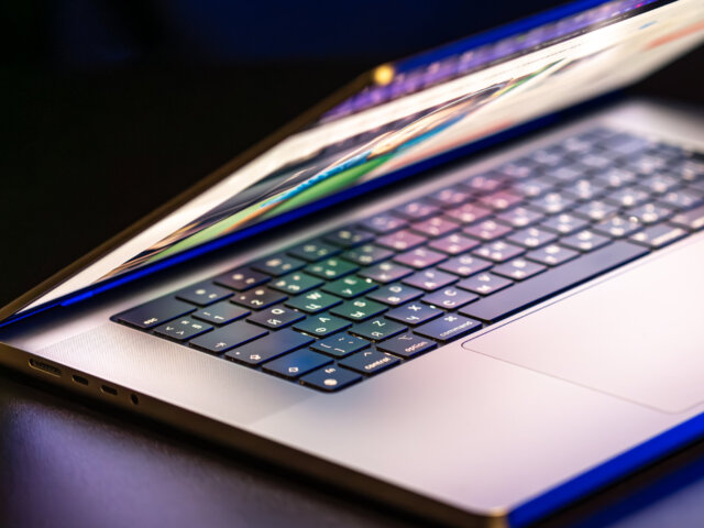 A laptop computer with a half-open screen on a dark background.